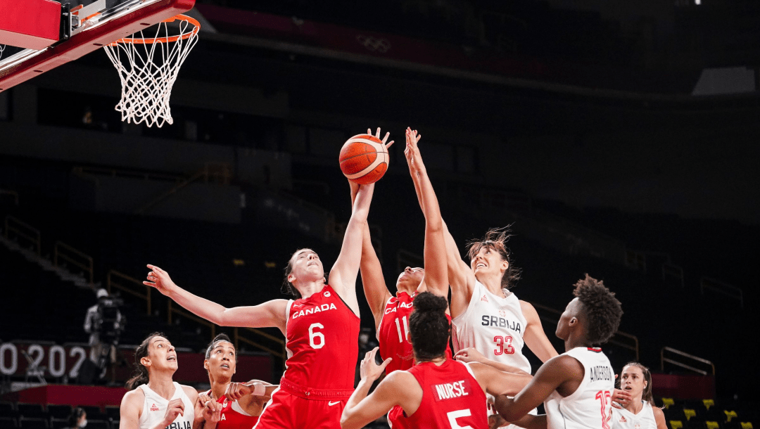 Des joueuses se disputent le ballon sous le panier lors d'un match de basketball.