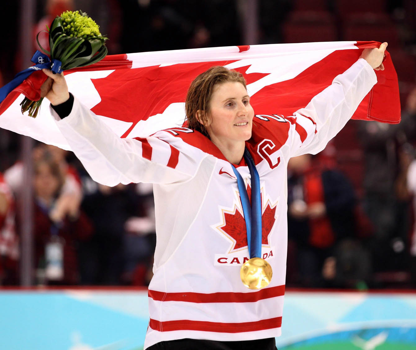 Hayley Wickenheiser, médaille au cou, porte le drapeau canadien