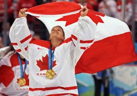 Kim St-Pierre, médaille au cou et tenant le drapeau du Canada