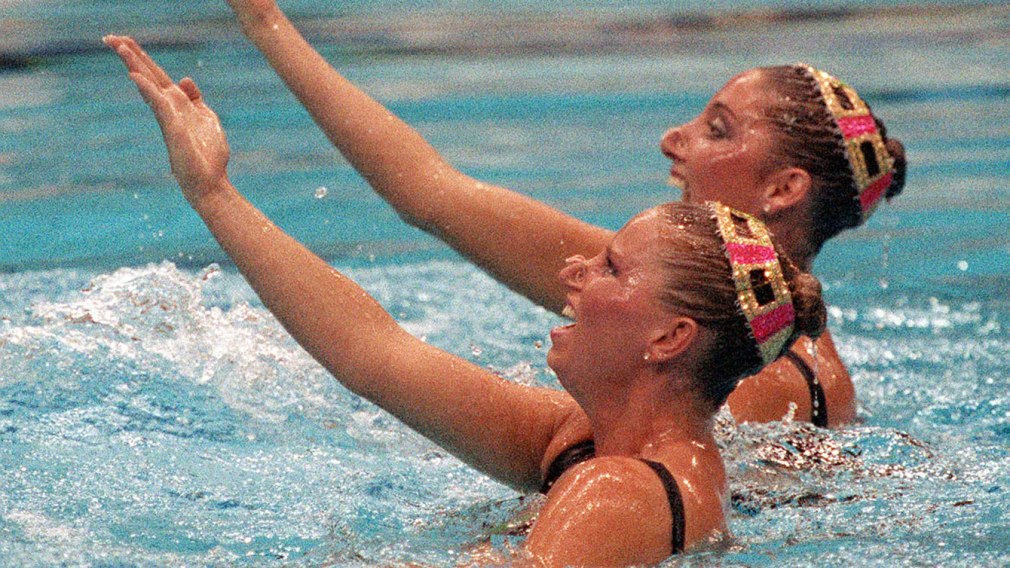 Deux nageuses lors de leur programme sortent les épaules et la main droite de l'eau.
