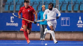 Two field hockey players chase the ball