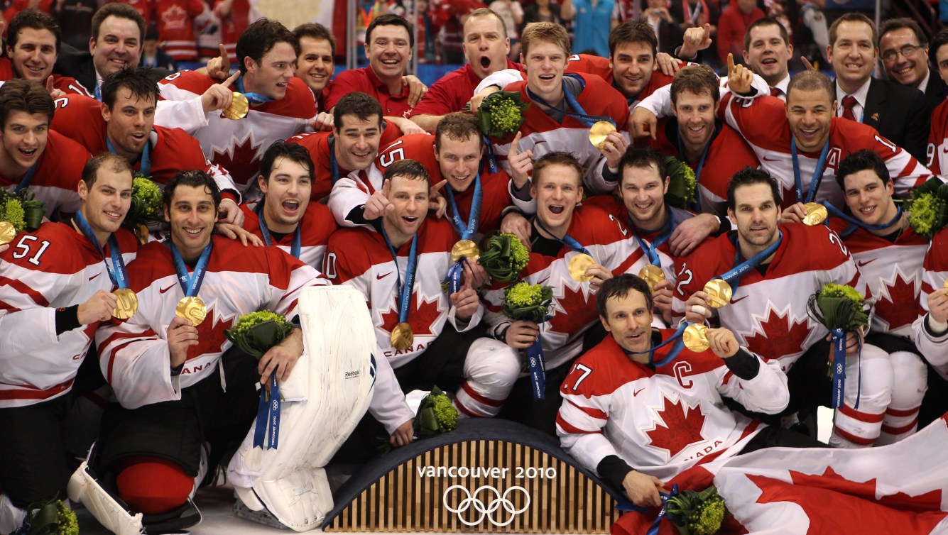 L'équipe de hockey masculine devant le podium olympique avec leur médaille d'or.