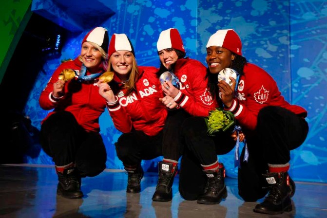 Les quatre Canadiennes accroupies montrent leur médaille.