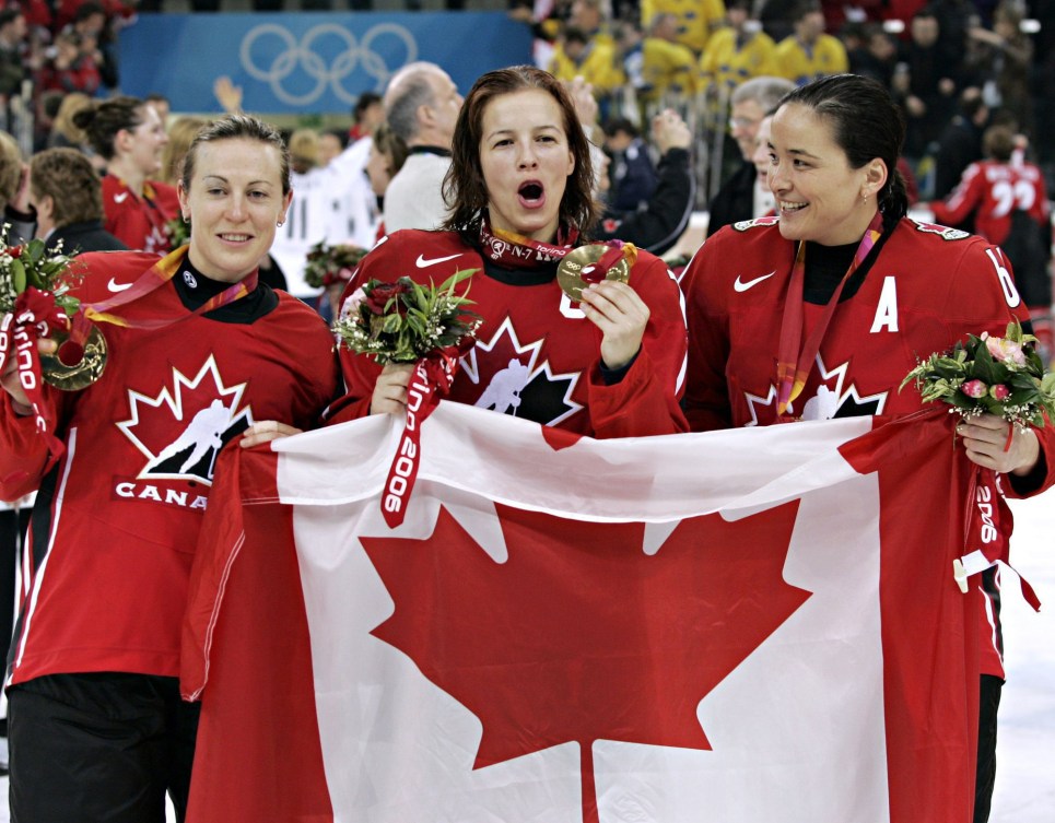 Jayna Hefford, à gauche, Cassie Campbell, au centre, et Vicky Sunohara, à droite, célèbrent en tenant le drapeau canadien.