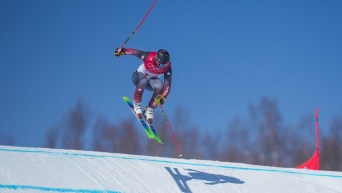 Un skieur effectue un saut lors de sa descente en ski cross