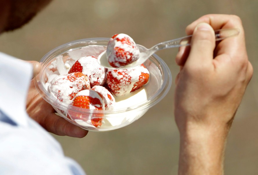 Un spectateur mange des fraises à la crème pendant le tournoi de Wimbledon, le jeudi 23 juin 2011. (AP Photo/Sang Tan)