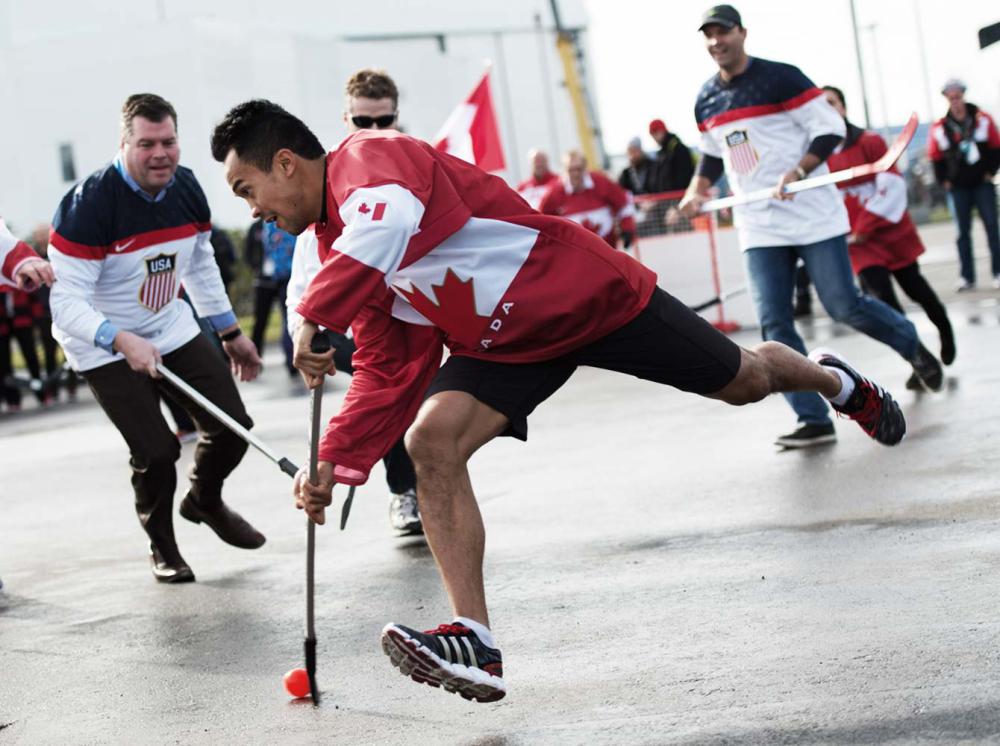 Le patineur de vitesse Gilmore Junio fait un lancer dans une partie amicale de hockey opposant le Canada et les États-Unis le 19 février 2014, aux Jeux olympiques d'hiver.