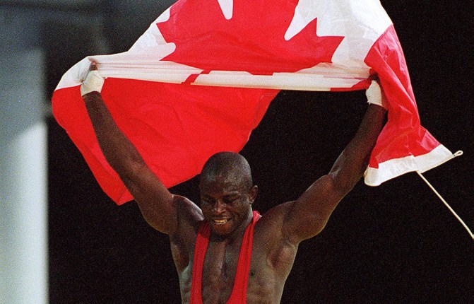 Canada's Daniel Igali waves the Canadian flag after winning the gold medal in wrestling at the 2000 Sydney Olympic Games. (CP Photo/ COC) Daniel Igali du Canada célèbre sa médaille d'or en lutte aux Jeux olympiques de Sydney 2000. (PC Photo/AOC)