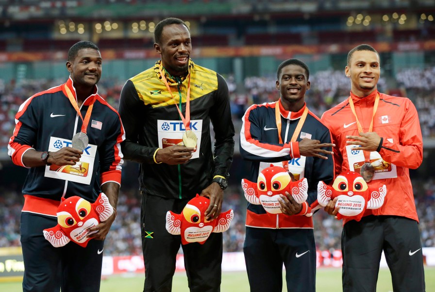 Le vainqueur de l'épreuve du 100 m Usain Bolt (Jamaïque) en compagnie de l'Américain Justin Gatlin (gauche), left, et les médaillés de bronze Trayvon Bromell des États-Unis et Andre De Grasse aux Championnats du monde IAAF d'athlétisme à Beijing, en Chine, le 24 août 2015. (AP Photo/Kin Cheung)