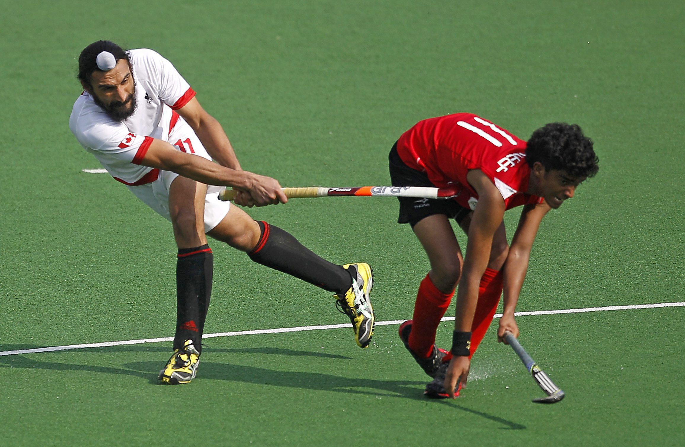 Karleef Abdullah Sasi de Singapour (droite) reçoit un coup de crosse dans les côtes gracieuseté du Canadien Jagdish Gill durant un match a New Delhi en Inde, le 21 février 2012. (AP Photo/Saurabh Das)
