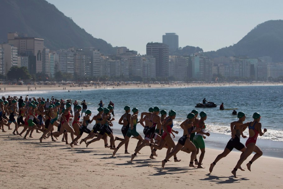 Athlètes s’élançant de la plage de Copacabana lors de l’épreuve féminine de triathlon de qualification olympique de Rio de Janeiro, 2 août 2015. (AP Photo/Felipe Dana)