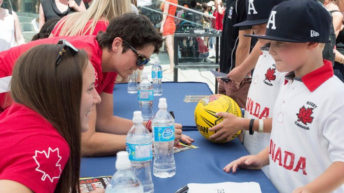 Britt Benn et Natasha Watcham-Roy signant des autographes aux partisans présents à la célébration de l’équipe canadienne de rugby, 2016. (Tavia Bakowski/COC)