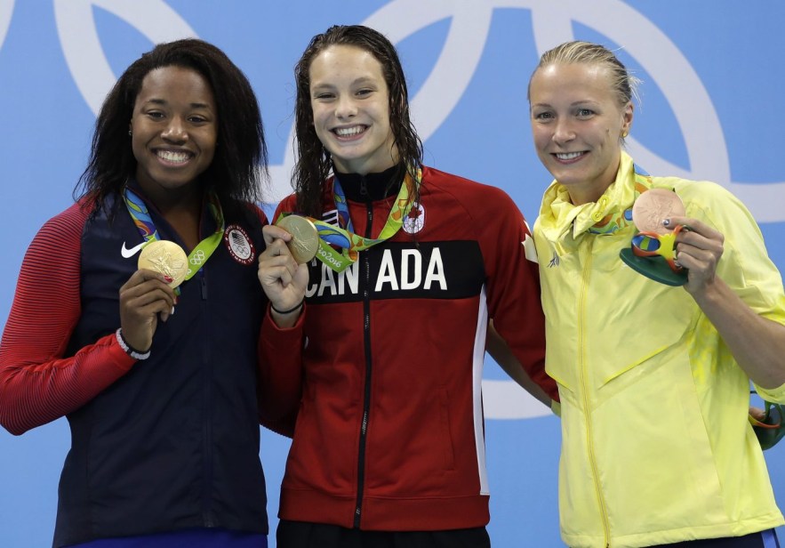 Les médaillées d'or du 100 m style libre Simone Manuel (gauche) et Penny Oleksiak (centre) avec la médaillée de bronze Sarah Sjostrom (droite) posent pour un photographe lors de la cérémonie des médailles. Jeux de Rio, 11 août 2016. (AP Photo/Michael Sohn)