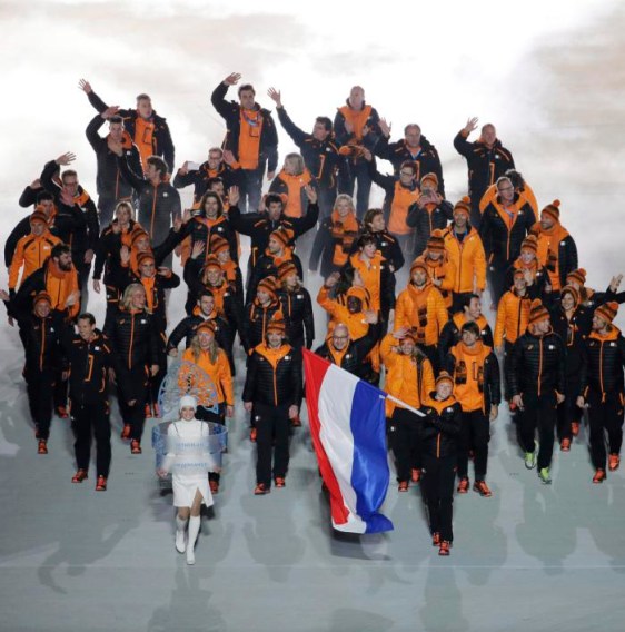 Jorien ter Mors du Pays-bas tient son drapeau national alors qu’il entre avec ses coéquipiers dans le stade lors de la cérémonie d'ouverture des Jeux olympiques d'hiver de 2014 à Sotchi, en Russie, le vendredi 7 février 2014. (AP Photo / Charlie Riedel)