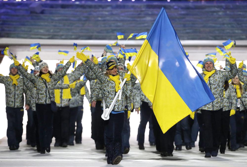 Valentina Shevchenko d'Ukraine porte le drapeau national alors qu'elle mène ses coéquipiers lors de la cérémonie d'ouverture des Jeux olympiques d'hiver de 2014 à Sotchi, en Russie, le vendredi 7 février 2014. (AP Photo / Mark Humphrey)