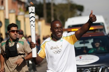 Bruni Surin court avec la flamme olympique avant les Jeux olympiques de Rio 2016.