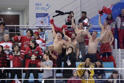 Les supporteurs canadiens réagissent au but de Wojtek Wolski durant un match préliminaire de hockey sur glace masculin du Canada contre la Suisse aux JO de 2018. Le 15 février 2018. (AP Photo/Julio Cortez)