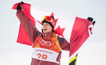 Alex Beaulieu-Marchand brandit le drapeau canadien après avoir remporté le bronze en ski slopestyle. LA PRESSE CANADIENNE/Jonathan Hayward