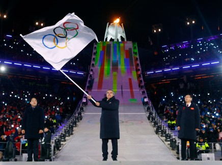 Le président du Comité olympique international, Thomas Bach, brandit le drapeau olympique, accompagné du maire de PyeongChang, Sim Jae-guk (gauche), ainsi que le maire de Beijing, Chen Jining (droite), lors de la cérémonie de clôture. (Kai Pfaffenbach/Pool Photo via AP)