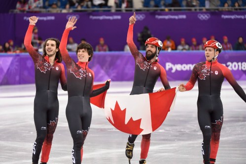 De gauche à droite: Samuel Girard, Charle Cournoyer, Charles Hamelin et Pascal Dion tiennent le drapeau canadien