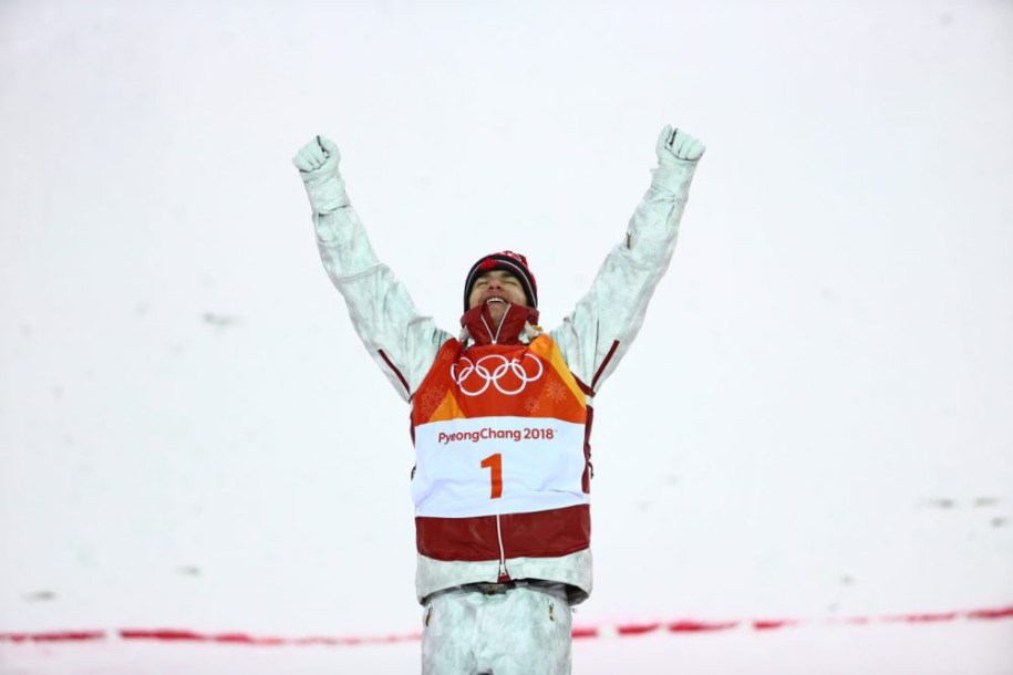 Mikaël Kingsbury, bras en l'air, célèbre sa victoire sur le podium