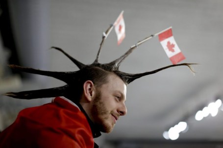 Un spectateur porte des drapeaux canadiens dans ses cheveux lors du match de curling double mixte de la demi-finale contre les athlètes olympiques de la Russie. Le 12 février 2018. (Photo: AP Photo/Natacha Pisarenko)