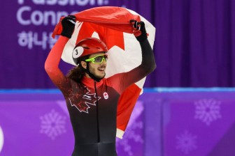 Samuel Girard soulève le drapeau canadien après avoir remporté la médaille d'or au 1000 m. (Photo par Vincent Ethier/COC)