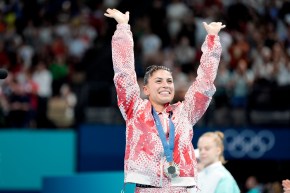 Sophiane Méthot lève les deux bras avec sa médaille de bronze autour du cou.