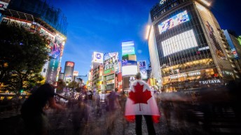 Une personne pose avec le drapeau canadien au centre-ville de Tokyo