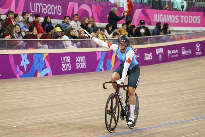 Kelsey Mitchell souriante sur son vélo après avoir remporté une médaille.