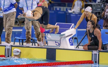 Des athlètes encouragent une nageuse qui plonge dans la piscine pendant une course