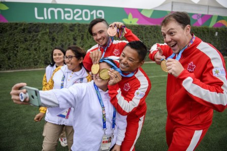 Eric Peters, Crispin Duenas et Brian Maxwell posent avec leurs médailles d'or et des bénévoles aux Jeux panaméricains de Lima, au Pérou, le 11 août 2019. Photo : Christopher Morris/COC