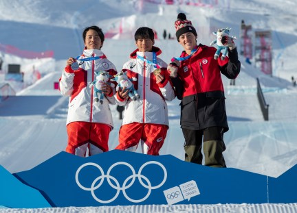 Trois athlètes sur le podium devant une piste de big air