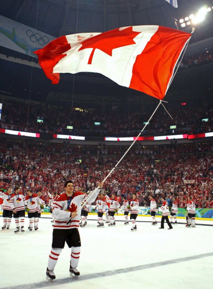 Sidney Crosby tient le drapeau canadien sur la patinoire