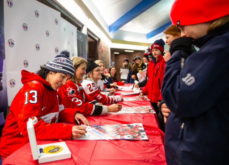 Des hockeyeuses canadiennes signent des autographes.