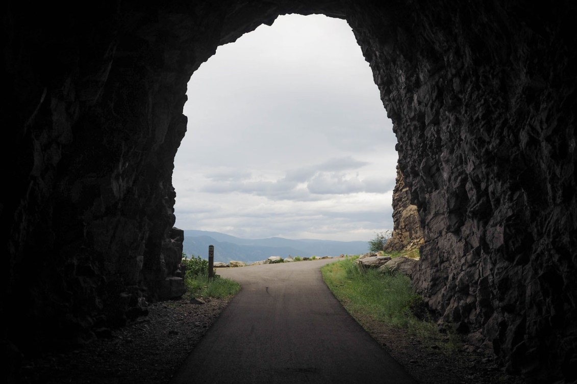 La fin d'une grotte, qui s'ouvre sur une piste cyclable et la vue d'une forêt.