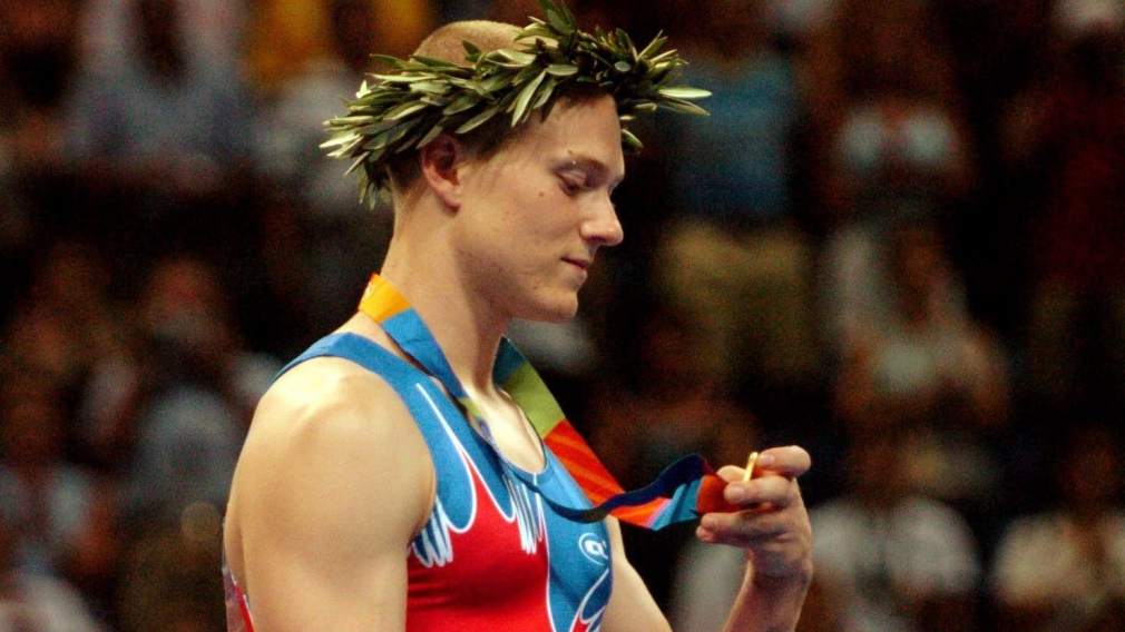 Un gymnaste regarde sa médaille d'or lors de la cérémonie des médailles