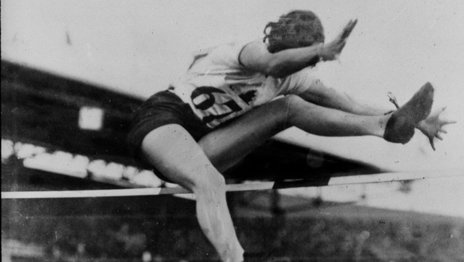 Une sauteuse en hauteur passe par dessus la barre en effectuant un coup de ciseaux aux Jeux olympiques de 1928