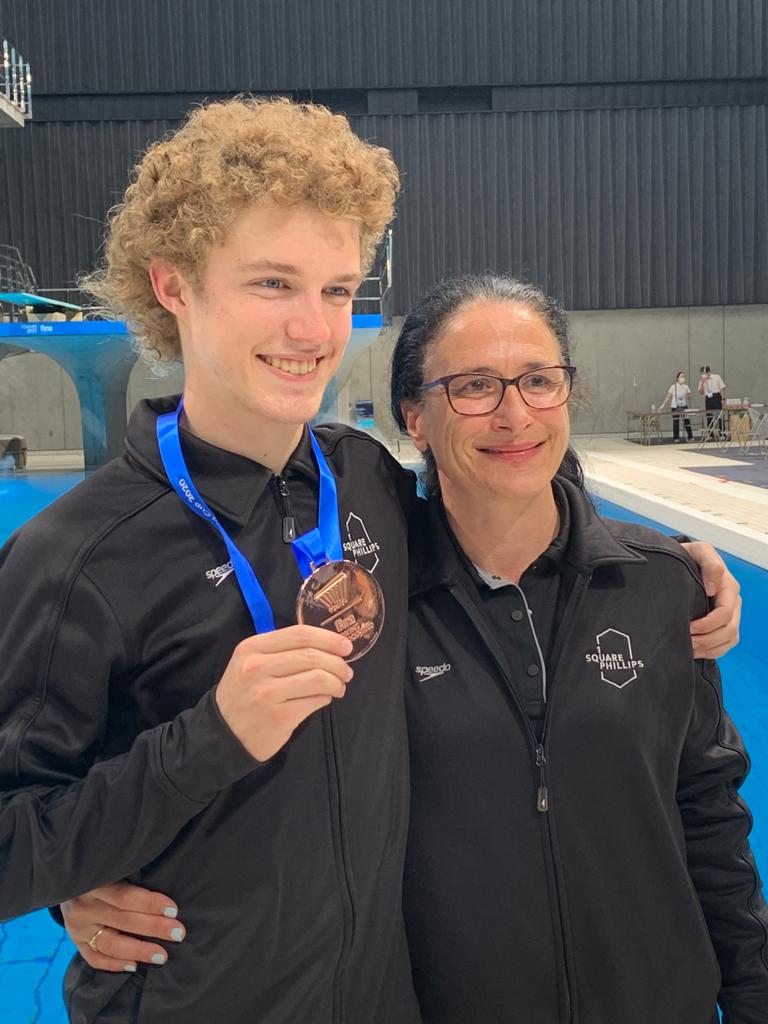 Un plongeur, une médaille à son cou, pose avec son entraîneure.