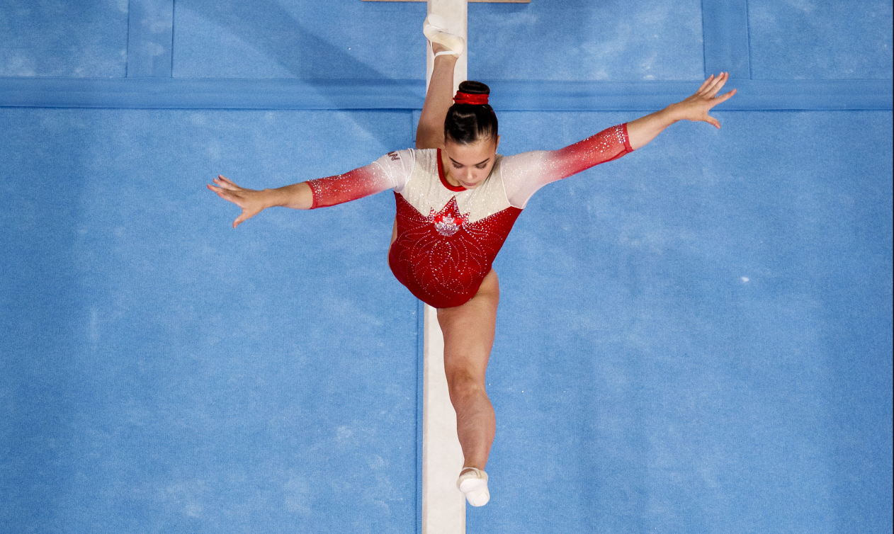 Une gymnaste en plein saut sur la poutre 