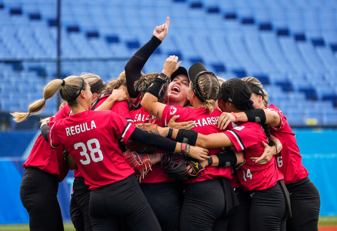 The Canadian women's softball team celebrates on the field.