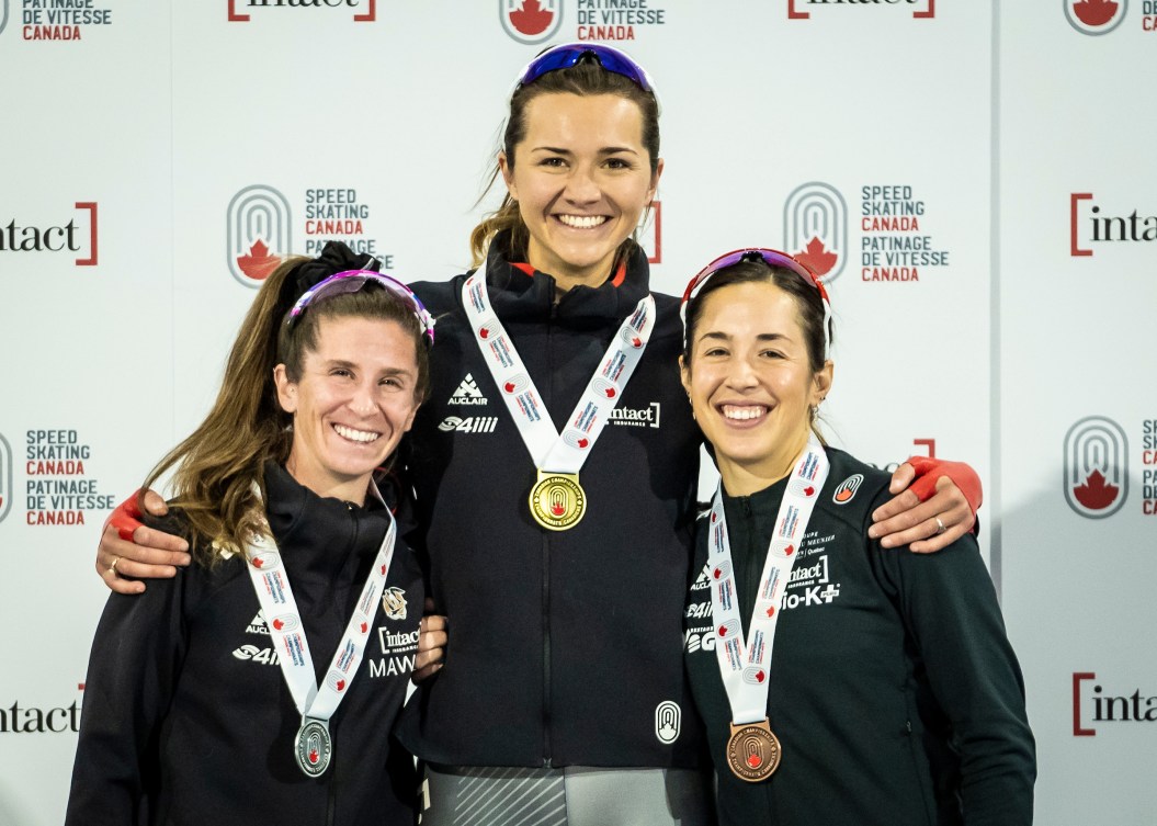 Trois patineuses avec leur médailles autour du cou. 