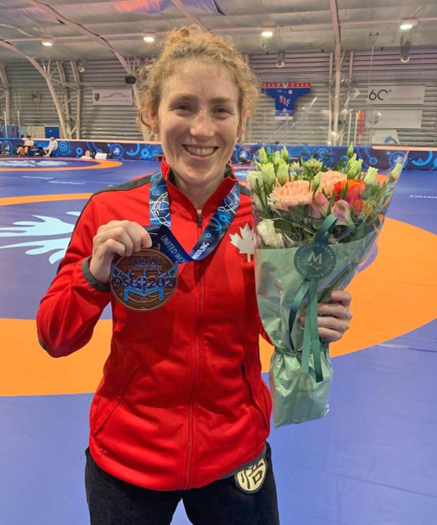 Samantha Stewart pose avec sa médaille de bronze des Championnats du monde à Oslo dans la main droite et des fleurs dans la main gauche..