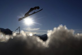Une athlète de saut à ski semble voler au-dessus des nuages.