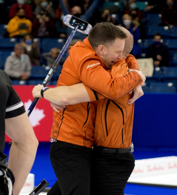 Deux joueurs de curling se serrent dans les bras suite à leur victoire