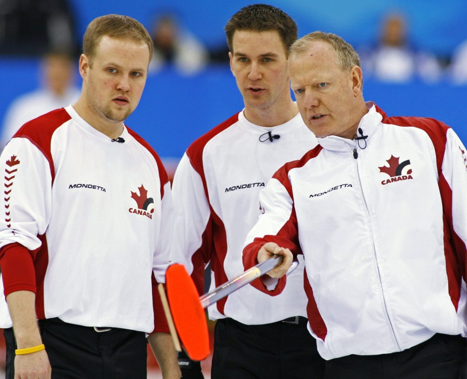 Trois joueurs de curling élaborent une stratégie de jeu lors d'un match