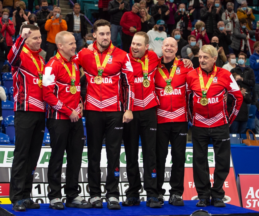 Une équipe de curling sur le podium avec leur médaille d'or