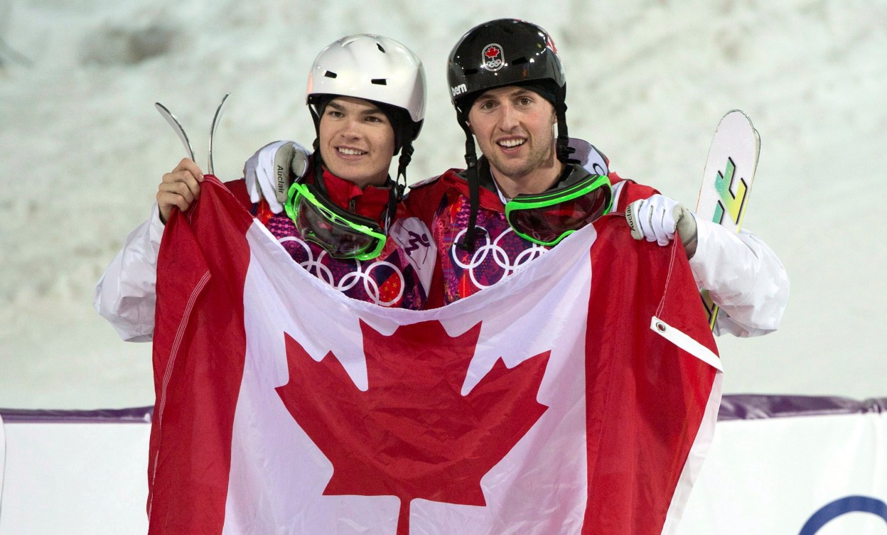 Mikaël Kingsbury et Alex Bilodeau tiennent le drapeau canadien dans leur mains. 