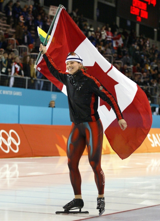 Catriona Le May Doan agite le drapeau canadien debout sur la glace.