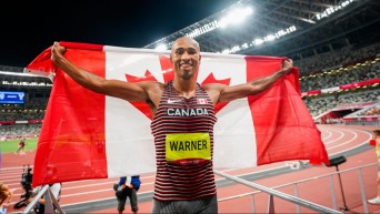 Damian Warner pose avec le drapeau canadien.